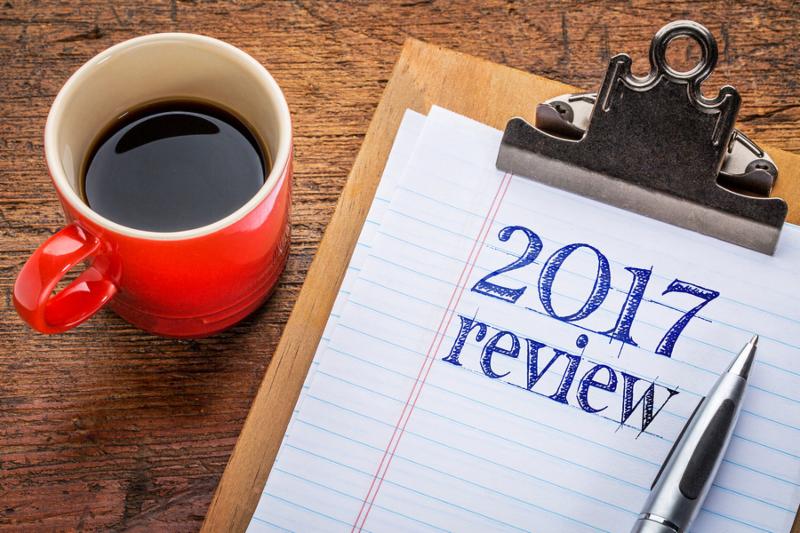 2017 year review on clipboard and coffee against grunge wood desk