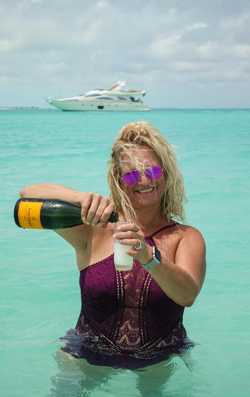Malaka pours Champagne in front of yacht