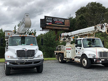 Power line trucks parked in front of a billboard for Southern Distilling Co.
