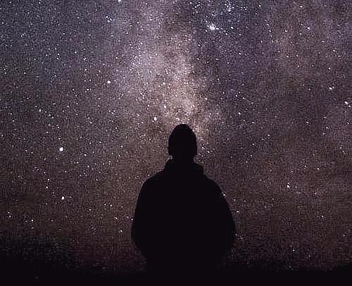 Silhouette of a man looking into a starry night