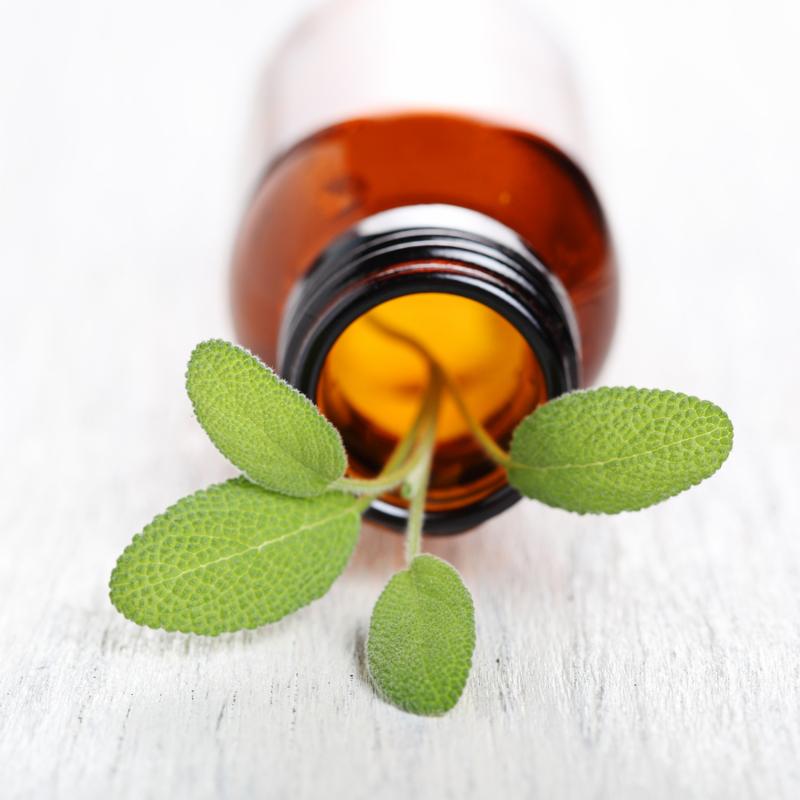 Sage herb leaves and an aromatherapy essential oil bottle
