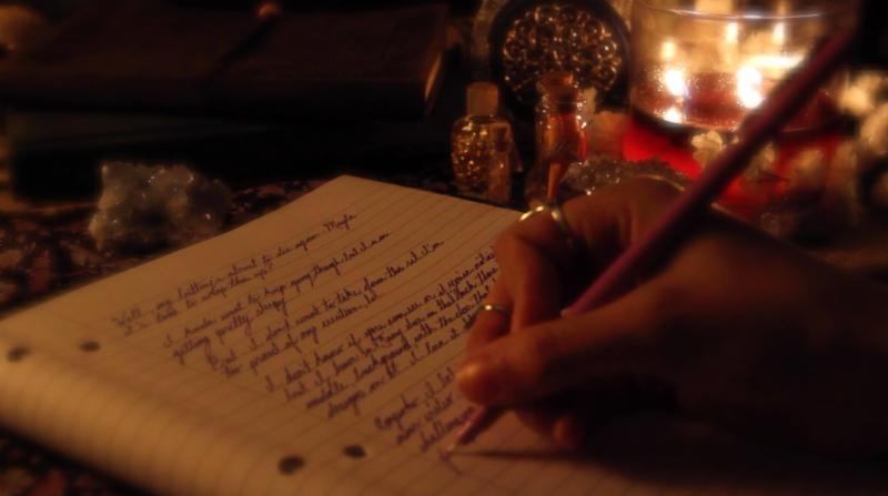 человек пишет в блокноте при свечах