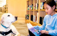 Child reading aloud to dog