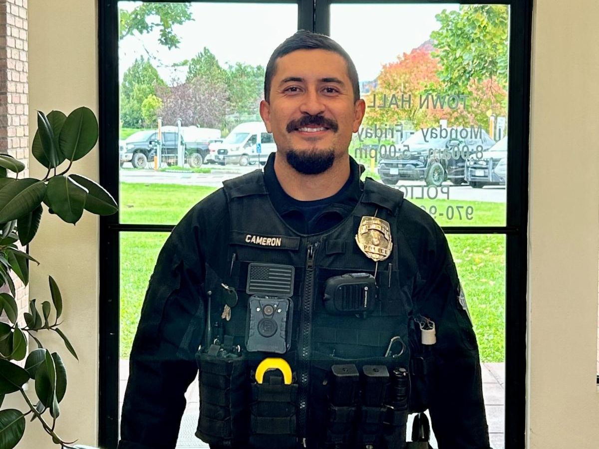 Police Officer standing in a lobby smiling at the camera.