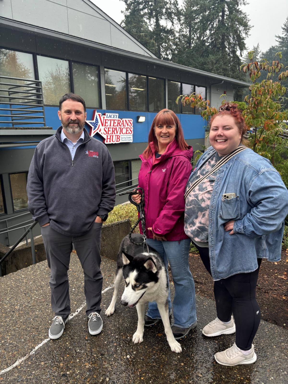 Three people stand with a dog.