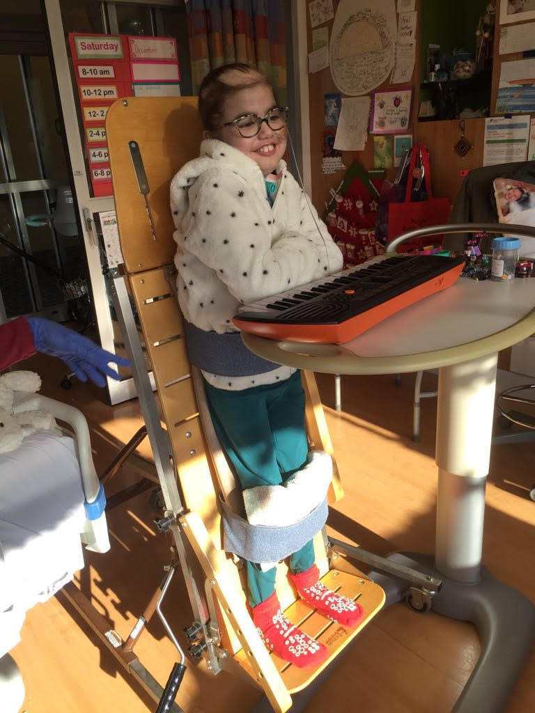 Picture of Isa standing at the keyboard and ready for music therapy. 