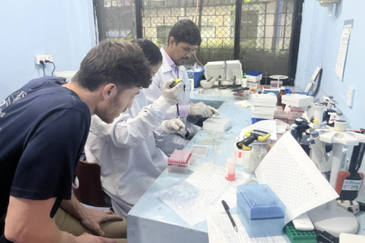 Three students working at a research lab bench