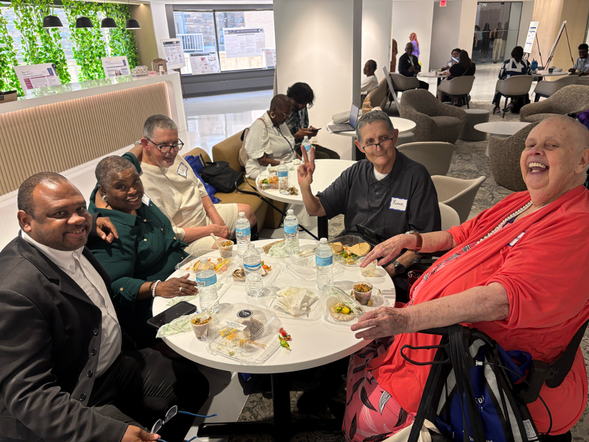 A group of Project ACTION! members smile and sit around a table