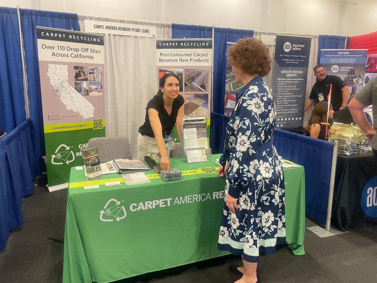 Abbie tabling at Conference, in discussion with attendee