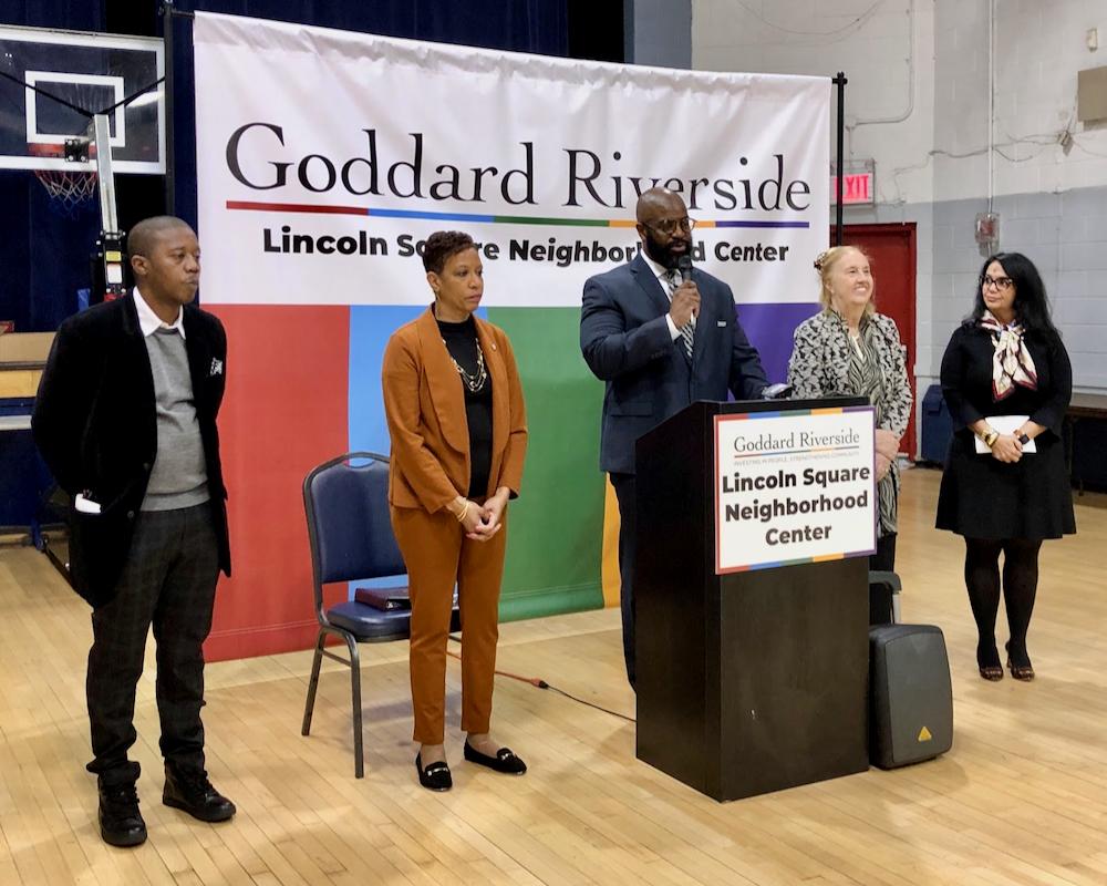 Several people stand in front of a Goddard Riverside Lincoln Square Neighborhood Center banner