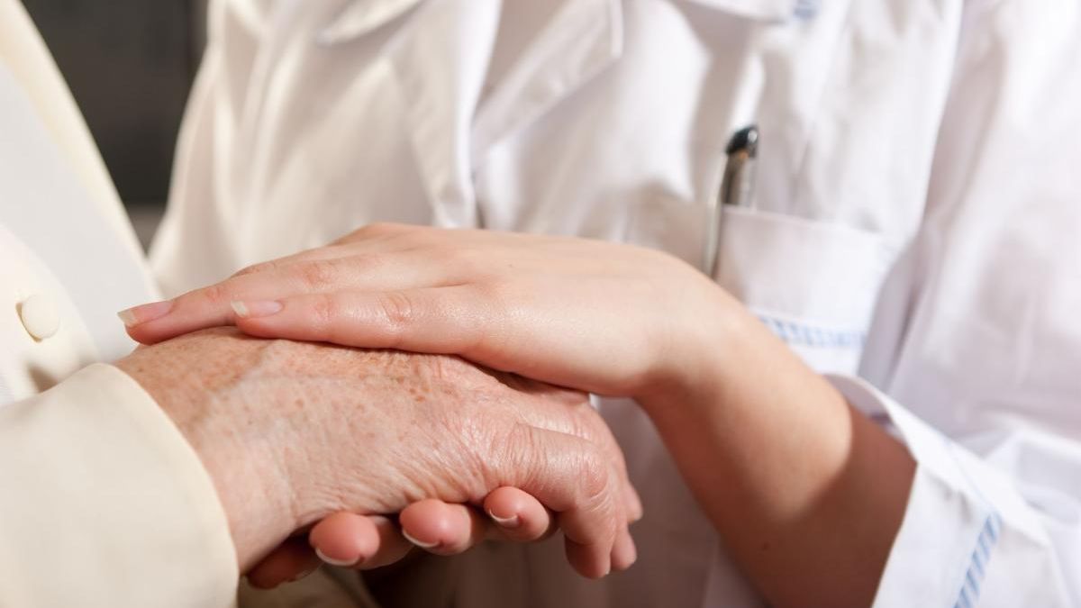 medical provider holding elderly person's hand
