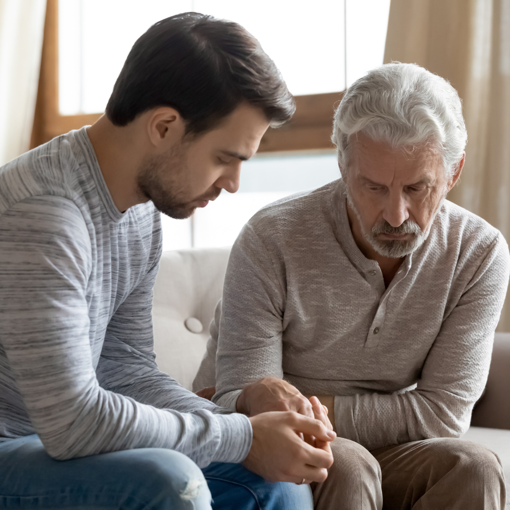 photo of a son and father with serious expressions sitting on couch 