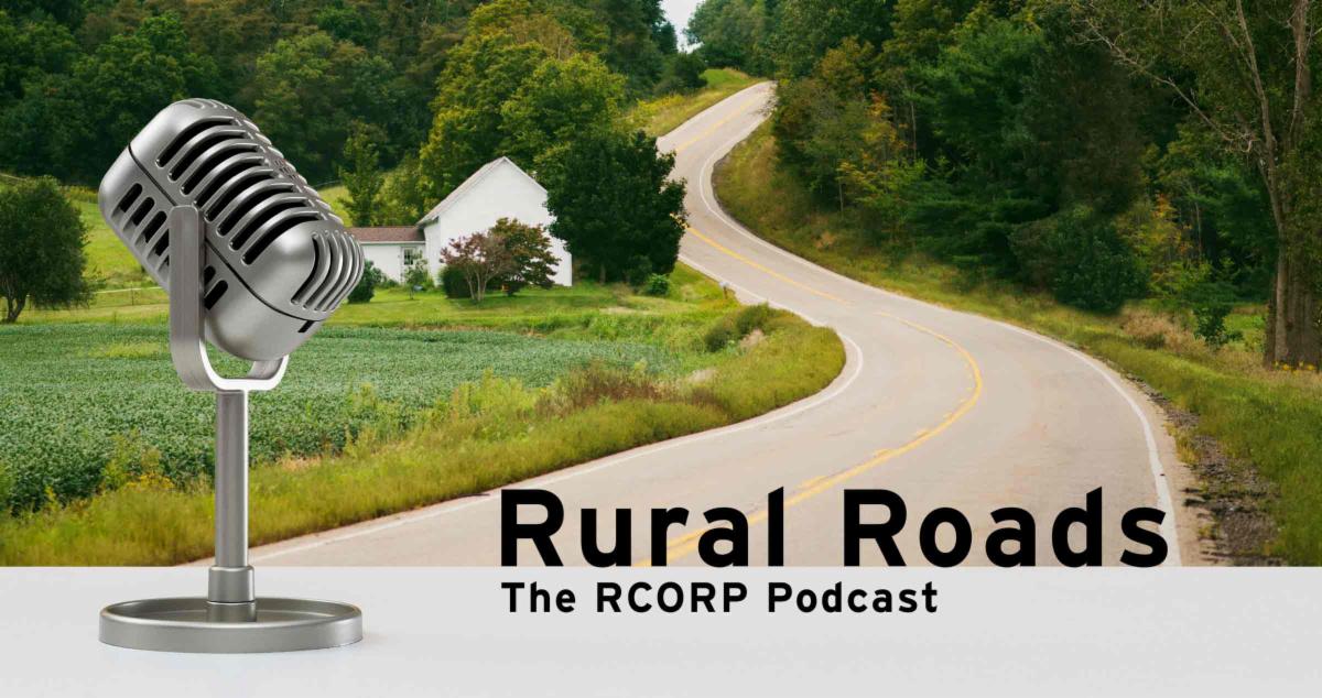a rural road winding through a field and by a house with an image of a microphone in foreground and text "rural roads"