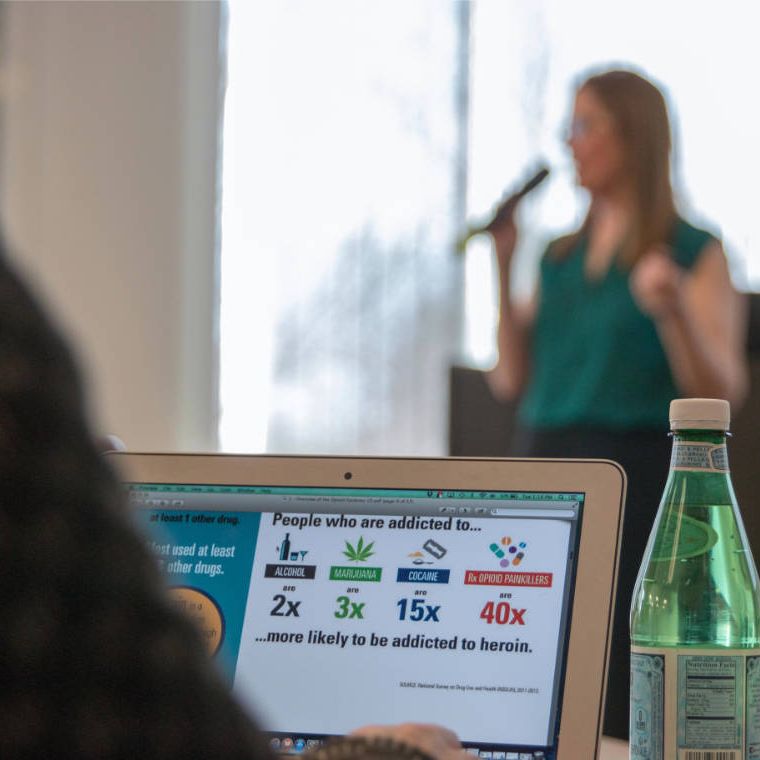 focus on attendees laptop screen with person presenting in background