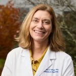 photo of Dr. Springer wearing white coat smiling outside 