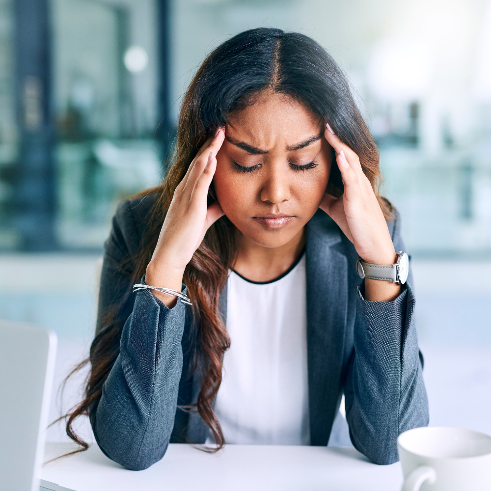 image of woman in pain sitting and pressing her hands to her temples