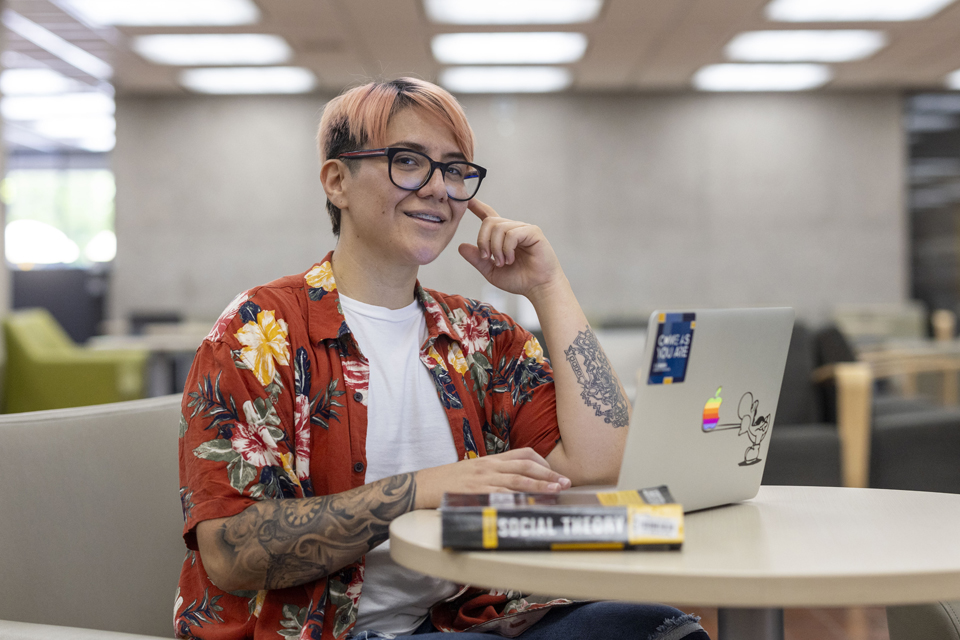 CSU Trustees' Award recipient Rebekah Reyes posting for a photo at a desk in the University Library.