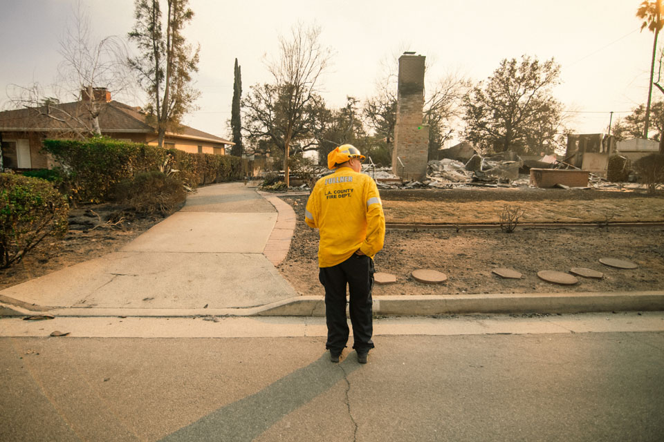A firefighter assesses the damage to a home burnt down during the Los Angeles County wildfires.