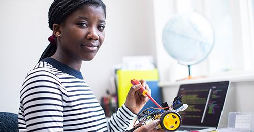 Black female student with a robotic vehicle and laptop that is displaying code