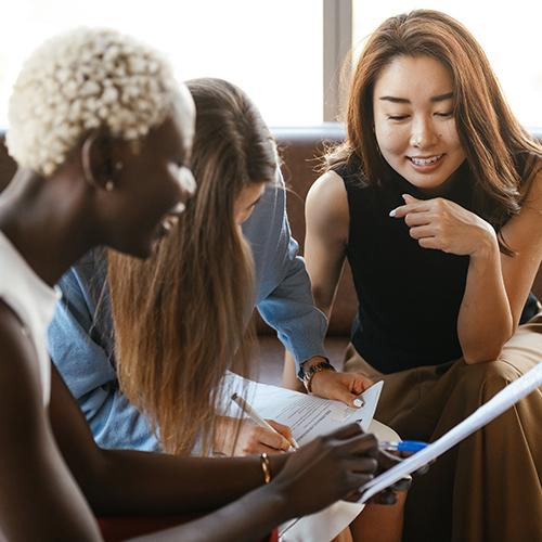 three people talk together while reviewing documents