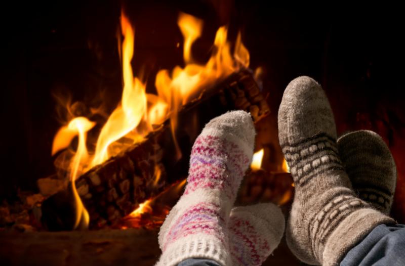 Two people's feet sitting by a fireplace