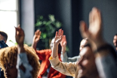 Image of people raising their hands together during a meeting