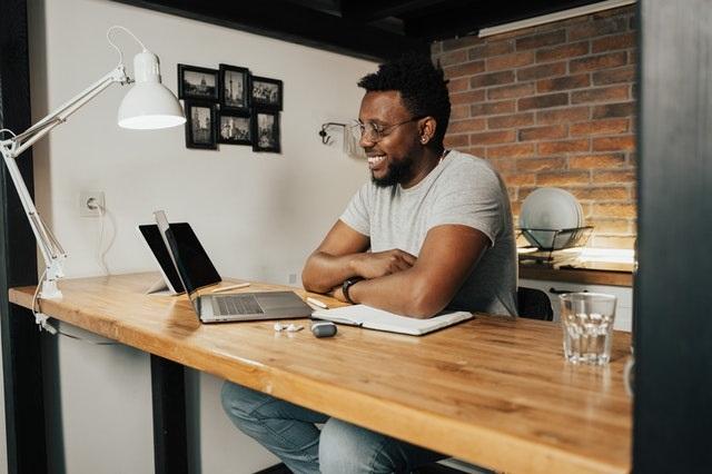 person smiling while sitting at a desk looking at a laptop