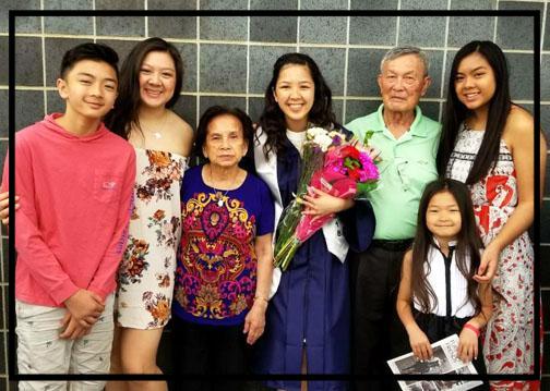 Taylor after her graduation ceremony holding flowers taking a photo with her family