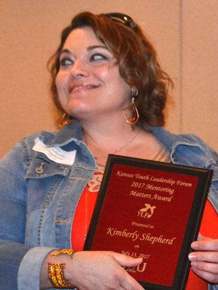 Kimberly Shepherd smiles as she holds her award plaque