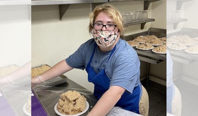 Sara wearing a mask and wrapping dessert bars in Saran Wrap in a kitchen