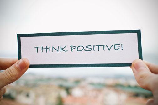 A person holding a sign that says Think Positive