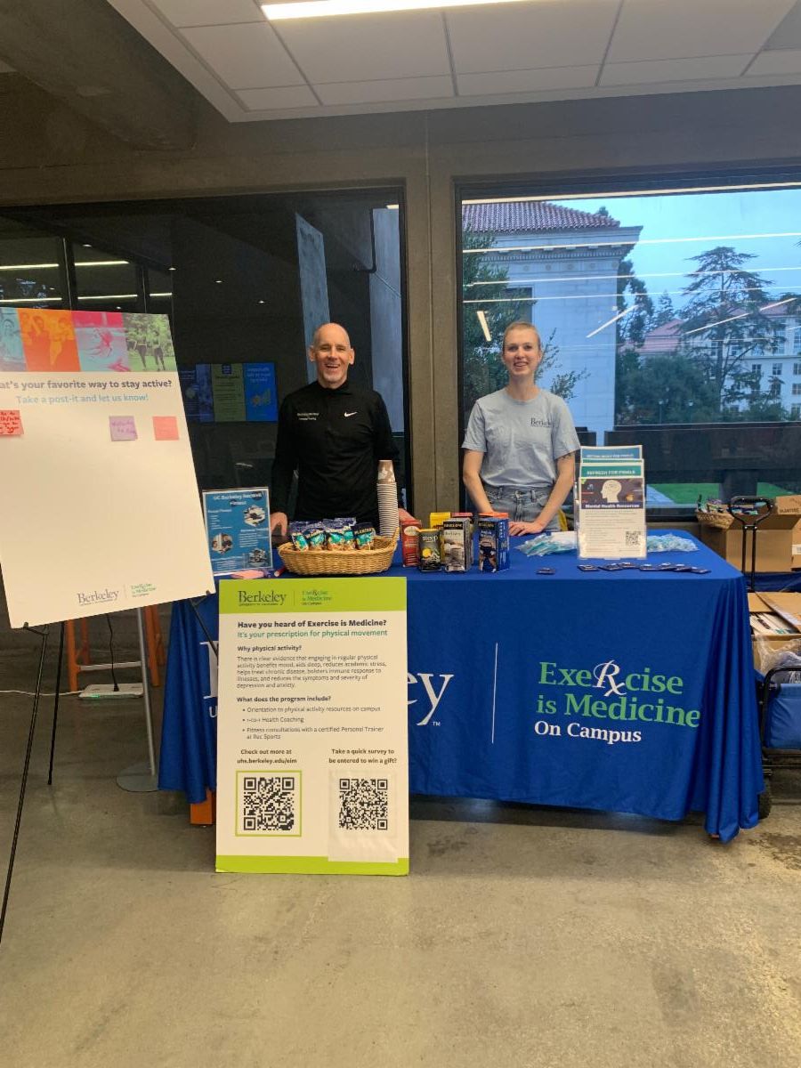Two people smiling behind the Exercise is Medicine Table at Moffit Library 