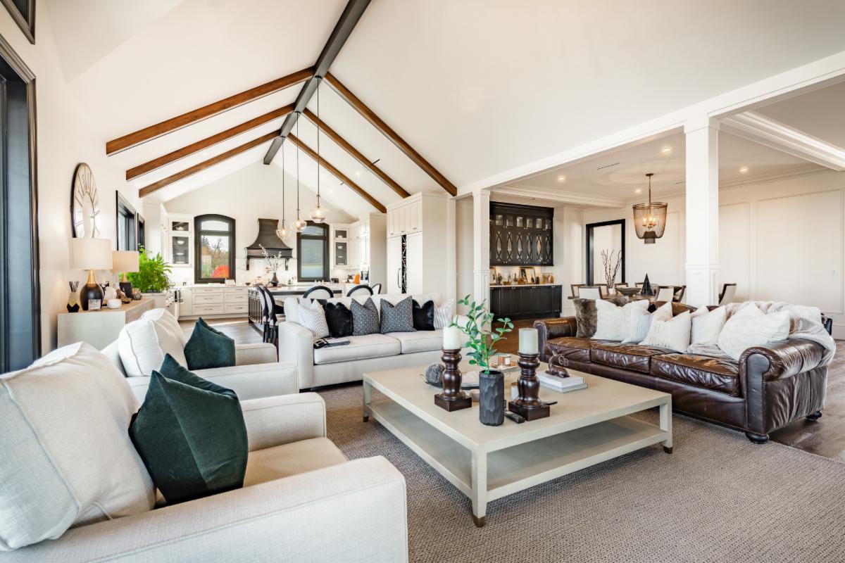 Very large living room interiors with luxurious furnishings and decor professionally decorated. Hardwood floors leather sofa fireplace animal hide skin rug throw blanket pillows rich wood tones and large windows upscale and elegant
