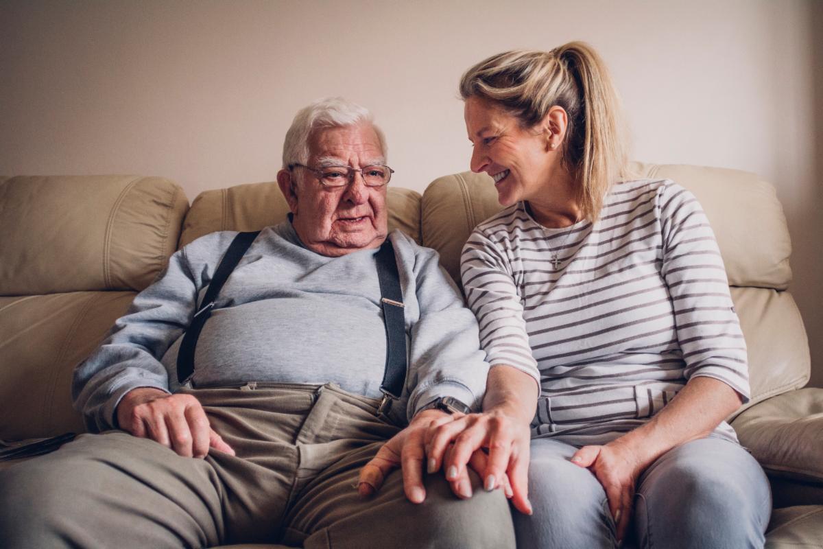 Daughter sitting with her elderly father holding hands