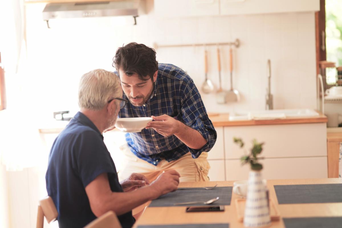 Young man presenting a bowl of soup to his father