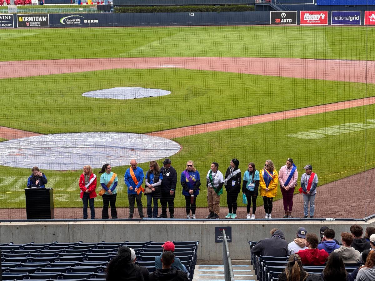 Photo of Out of the Darkness beading ceremony, with about a dozen people lined up representing different experiences related to suicide