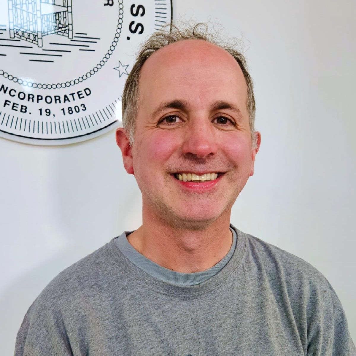 Headshot of Chris Ellis in a grey shirt he is smiling