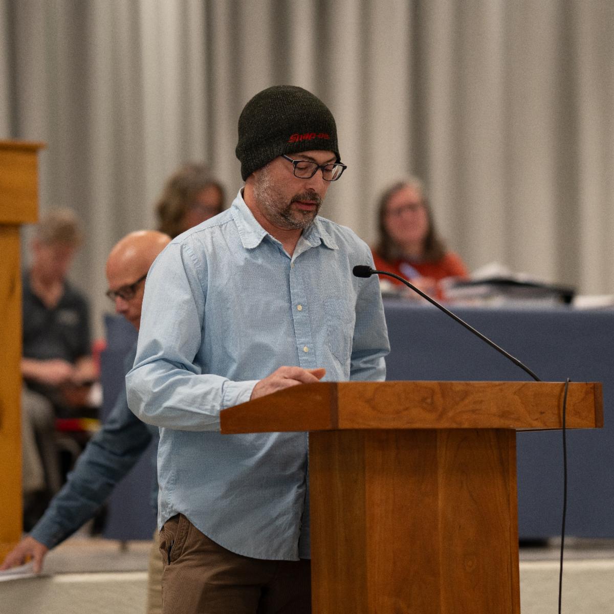 Alex wentworth is standing at a poduim at town meeting