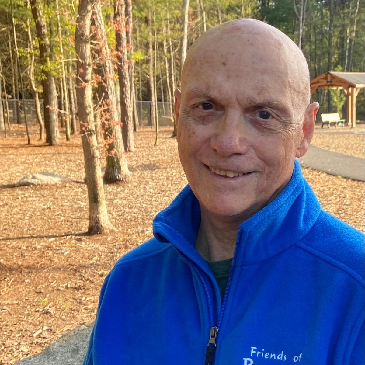 Carmen is at the Brewster Dog Park wearing a blue collared fleece he is smiling.