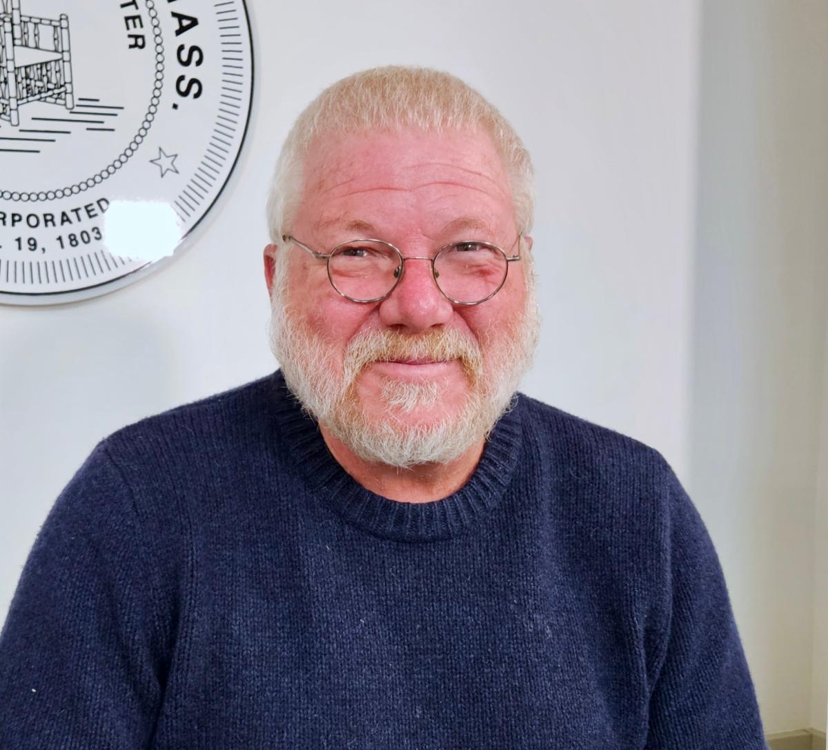 Headshot of Rolly Bassett wearing a blue knit sweater he is smiling