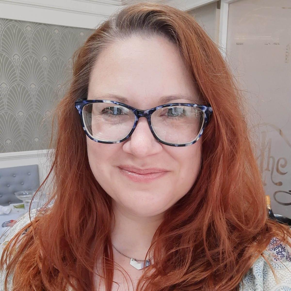 Headshot of Amanda Bebrin she is wearing glasses and has red hair.