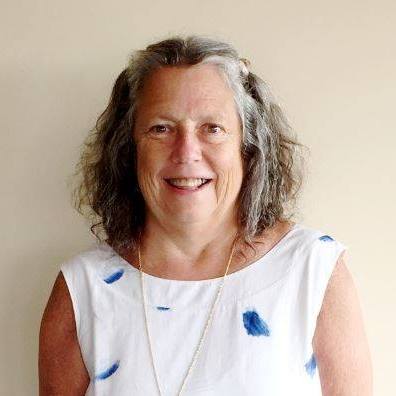 Picture of Caroline McCarley in a white shirt with her hair down she is smiling