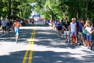 a mostly empty road lined with people watching a running race