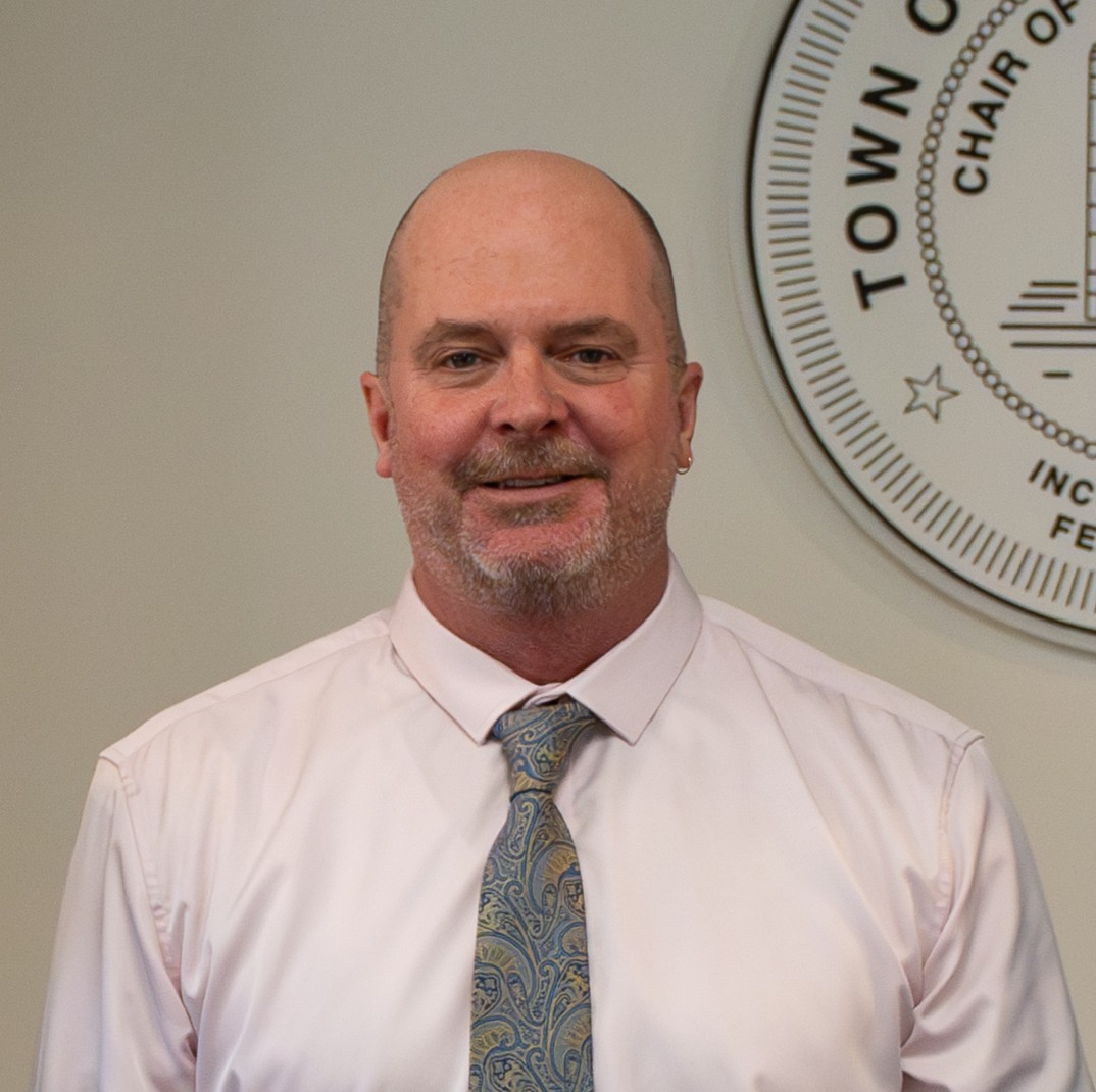Paul Anderson in a light pink shirt and paisely tie