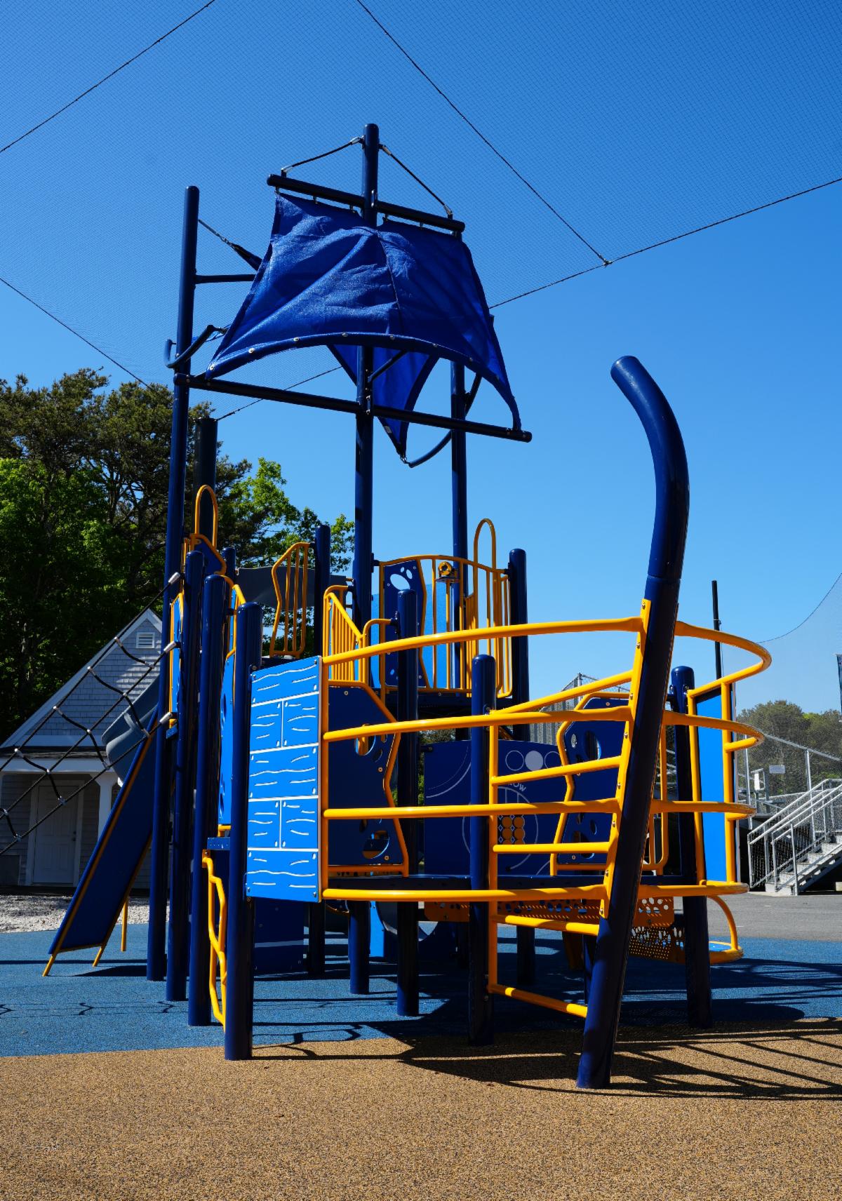 A blue and yellow ocean ship themed elementary school playground with slides and climbing