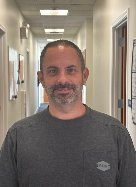 Matt Silva is wearing a dark shirt and is smiling slightly.