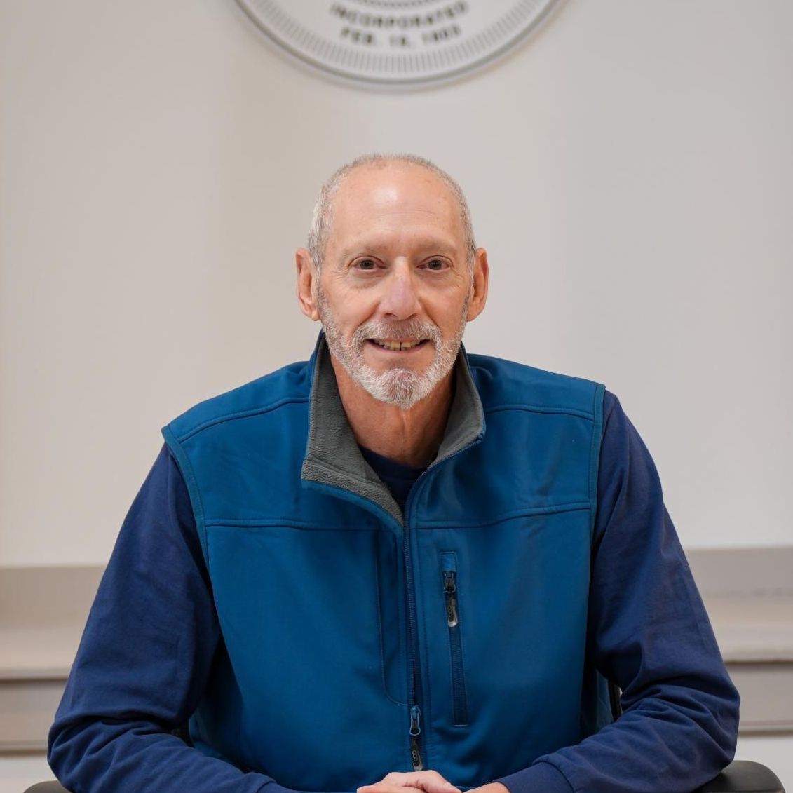 Robert Tobias posed for the picture is wearing a blue shirt and is smiling