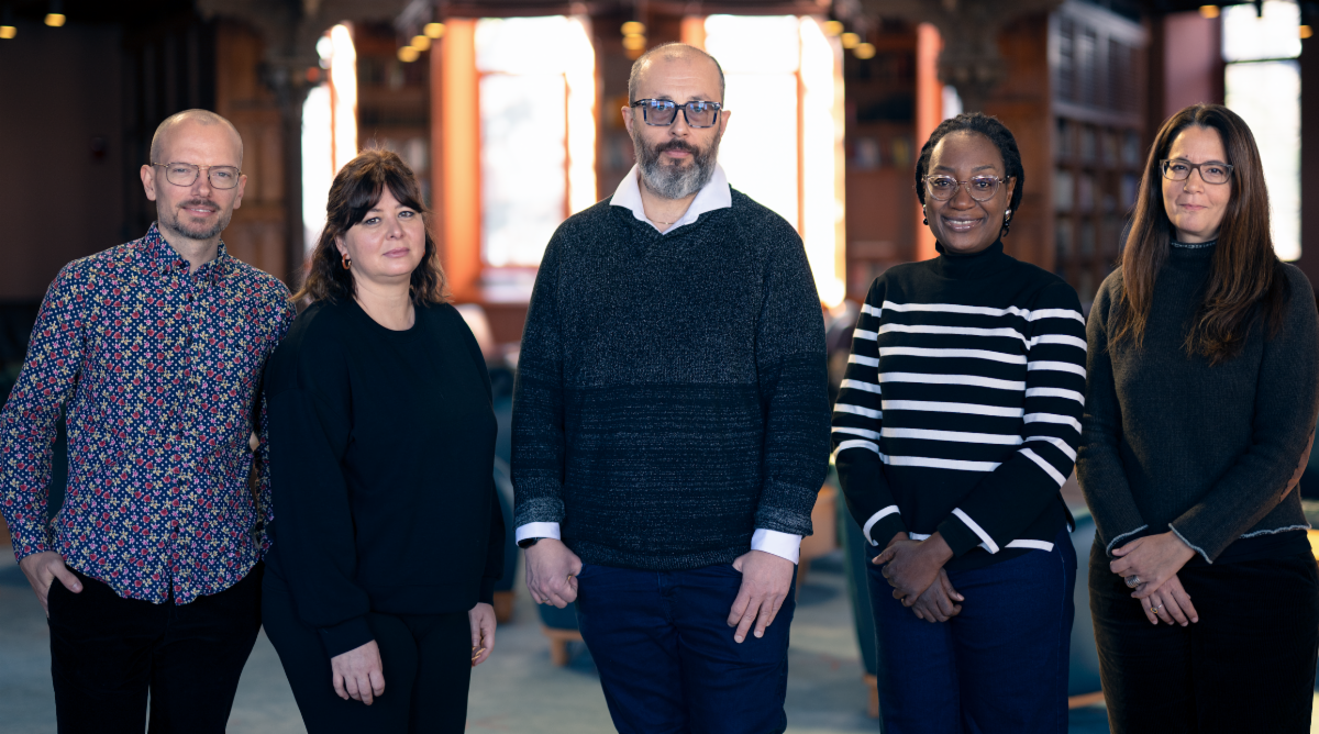 Five people standing together in a wood-paneled library.
