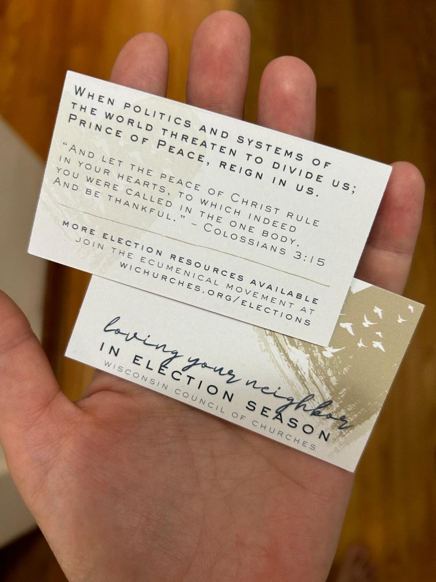 A white woman’s hand holding two prayer cards so that the back and front can be seen at the same time