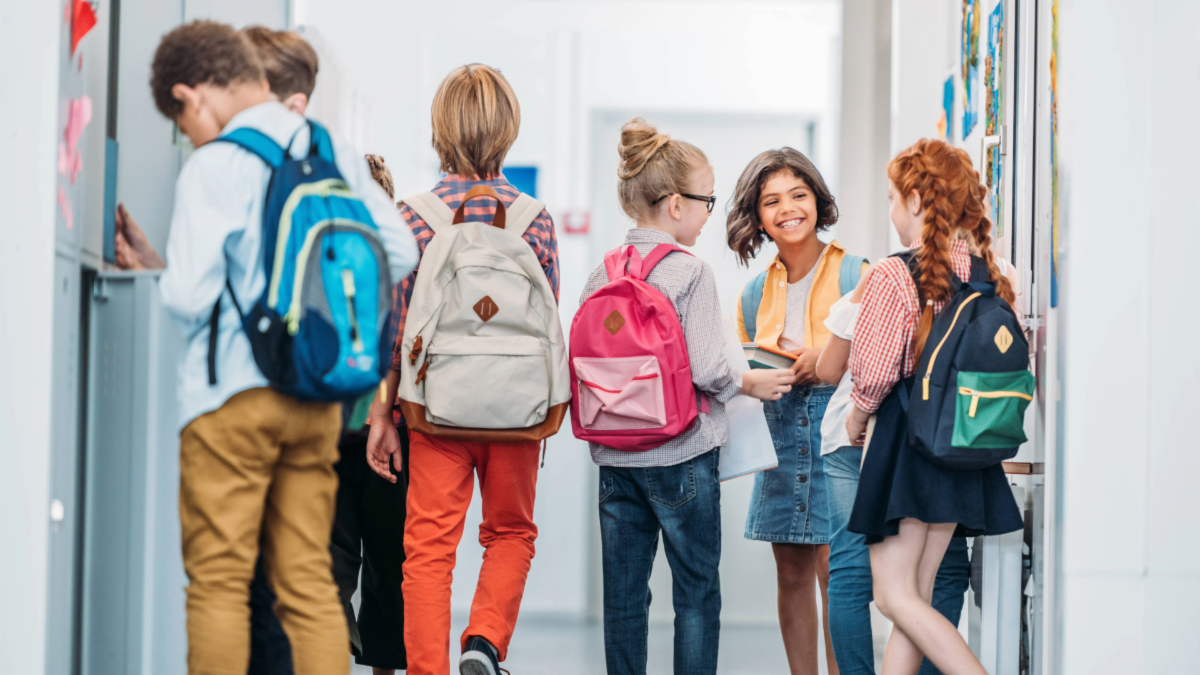 Students with backpacks talking in front of lockers at school